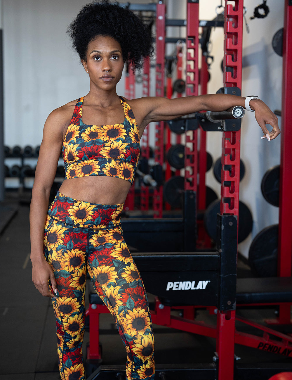 model wearing the sunflower with red flowers leggings and bra in the gym