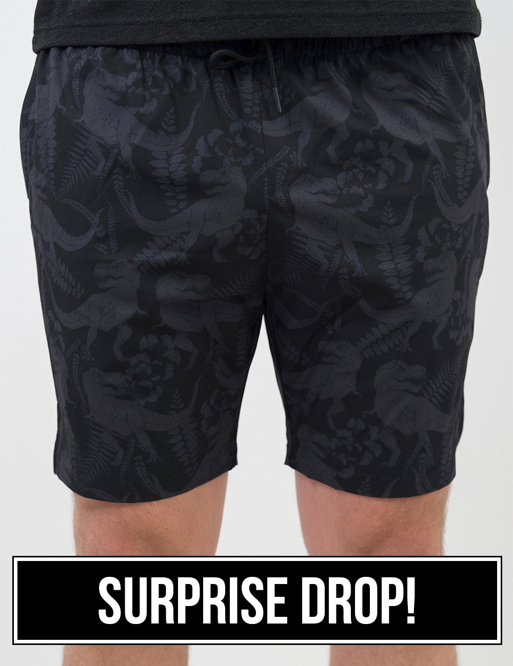 front of the black men's shorts with a tonal grey t-rex pattern against a white background, surprise drop