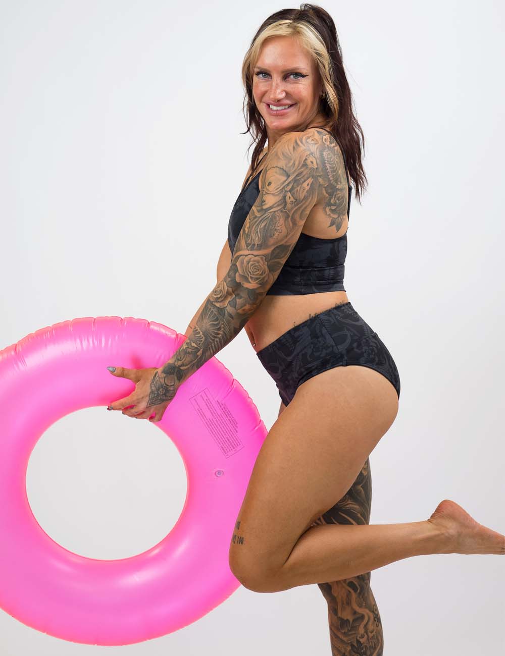model wearing dino bathing suit holding a pink inflatable tube