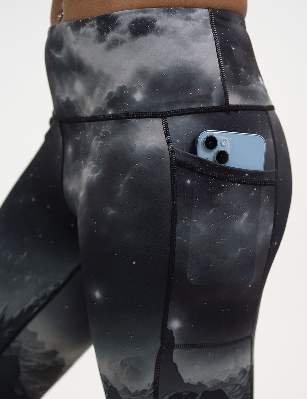 close up of the black leggings with mountain and star pattern with a phone in its pocket