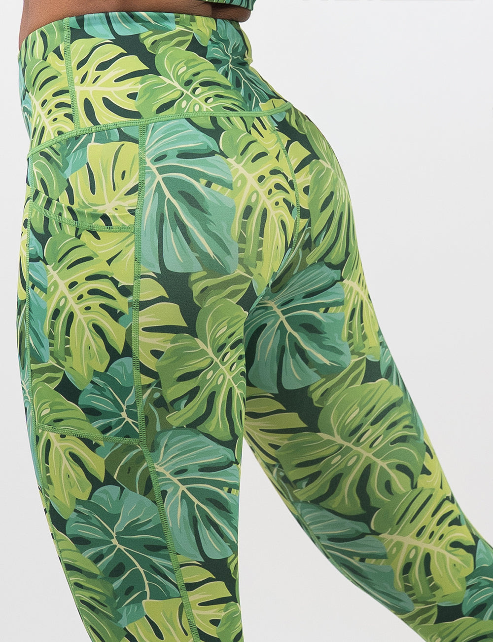 back of the green tropical leaves leggings against a white background