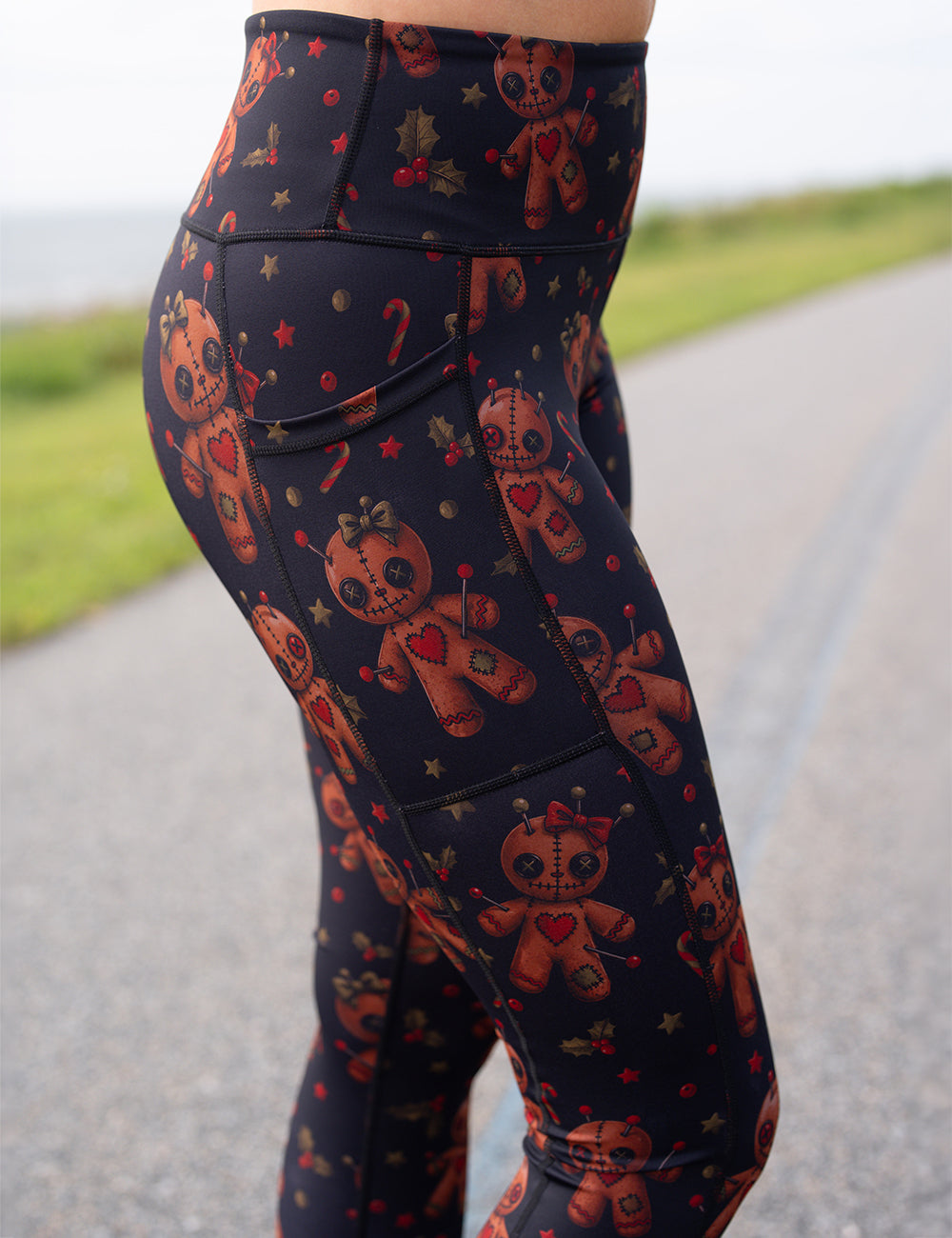 close up of the gingerbread voodoo dolls with pins in them surrounded by berries and stars on a black background leggings