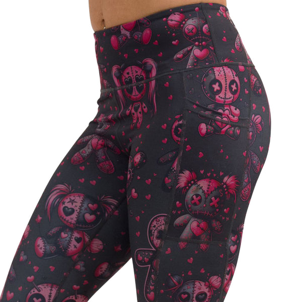 close up of pink voodoo doll with pink hearts pattern leggings against a white background
