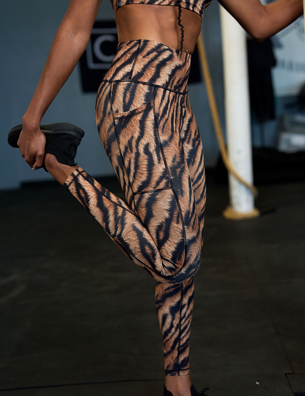 model wearing the tiger print full length leggings in the gym stretching