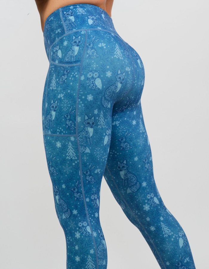 back of the blue leggings with foxes, owls, pine trees, and snow flakes against a white background