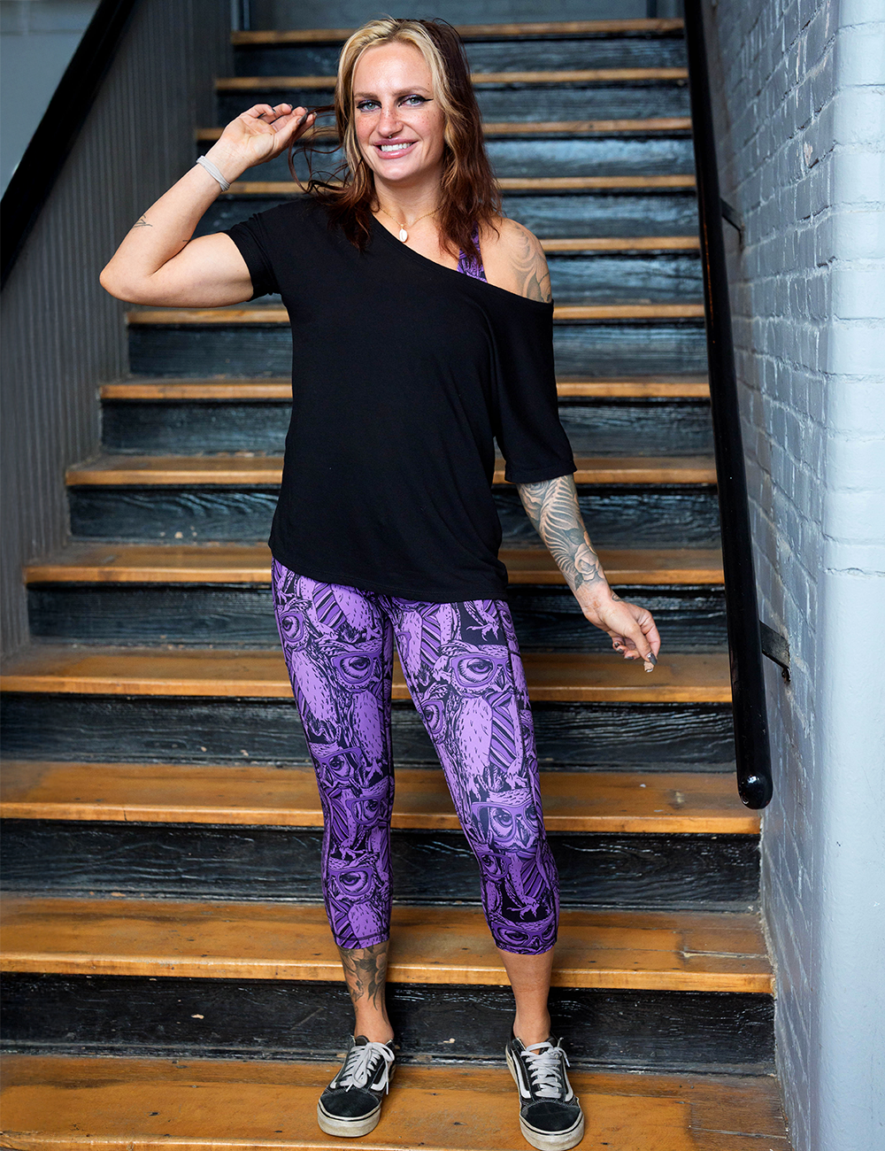 model wearing the purple owl wearing glasses and a tie print capri leggings in a stairwell