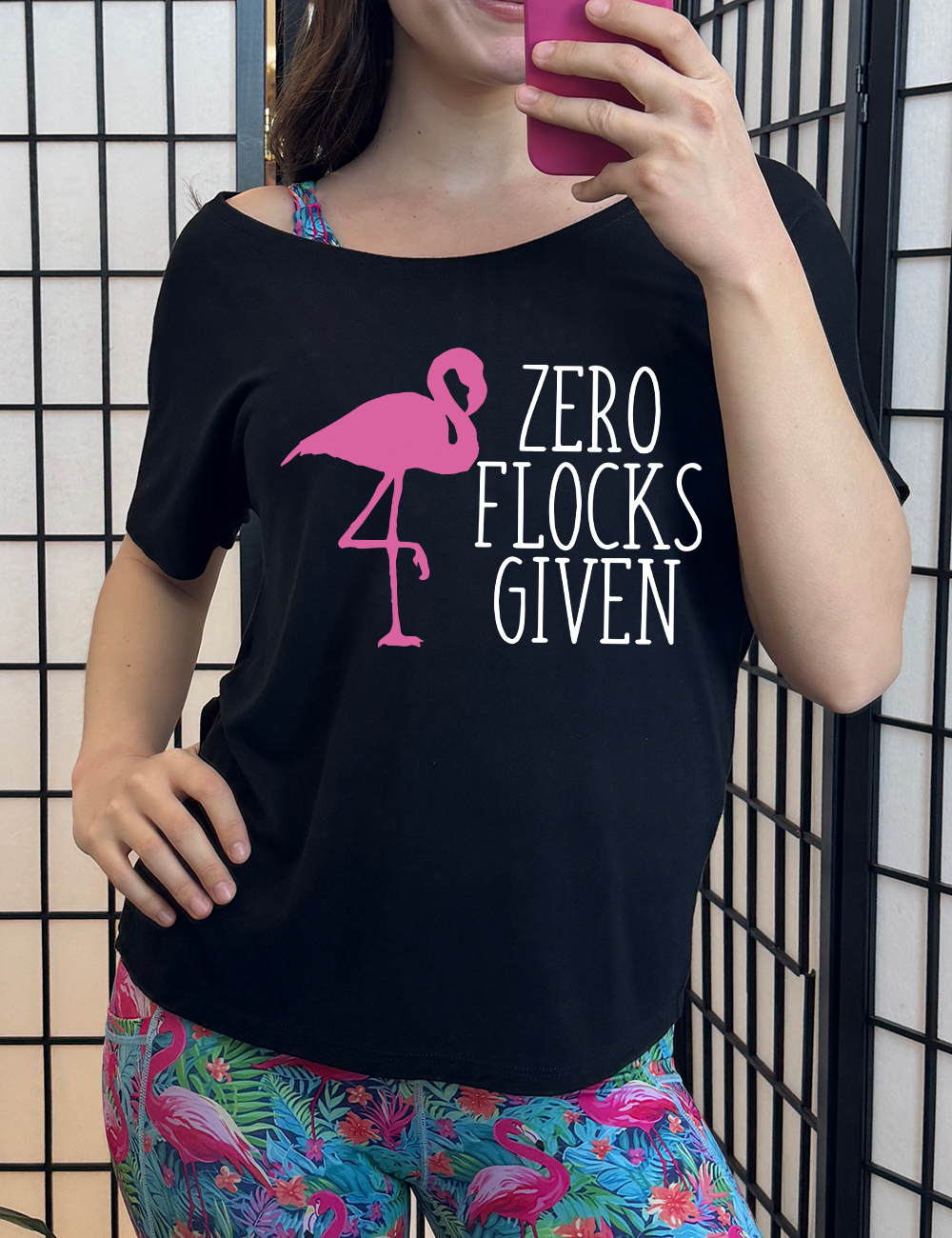 black slouchy tee with the words "zero flocks given" on it, with the pink silhouette of a flamingo, leg raised, next to the words