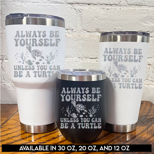 30oz white tumbler, 12oz black tumbler and 20oz white tumbler with silver saying "always be yourself unless you can be a turtle" with turtle cartoon, seaweed, shells and bubbles