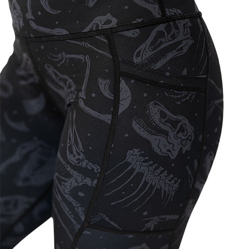 close up of pocket, black leggings with light grey dinosaur skull and bones pattern