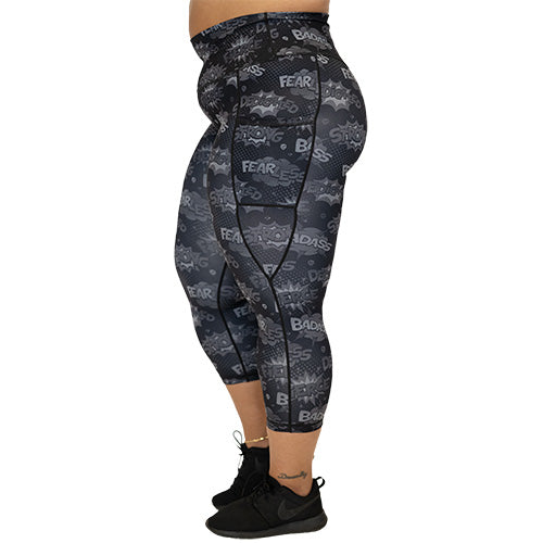 side view of capri length black leggings with comic book style action bubbles that say "badass", "fierce" and "dedication"