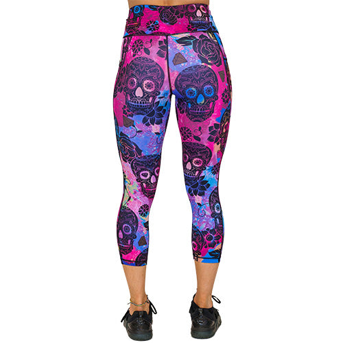 back view of capri length purple, pink and blue tie dye leggings with black skull and rose pattern