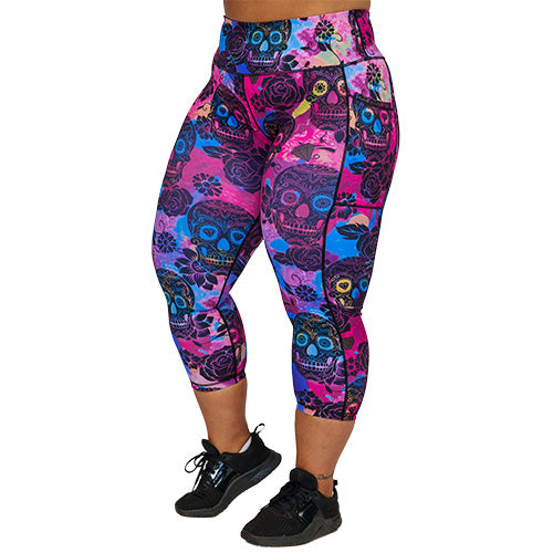front view of capri length purple, pink and blue tie dye leggings with black skull and rose pattern