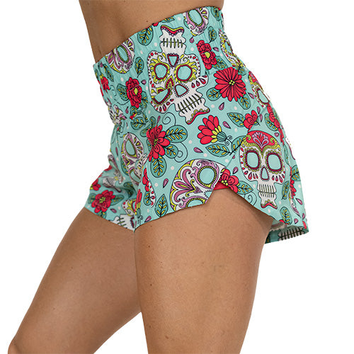 side view of teal, pink, white and yellow sugar skull print shorts