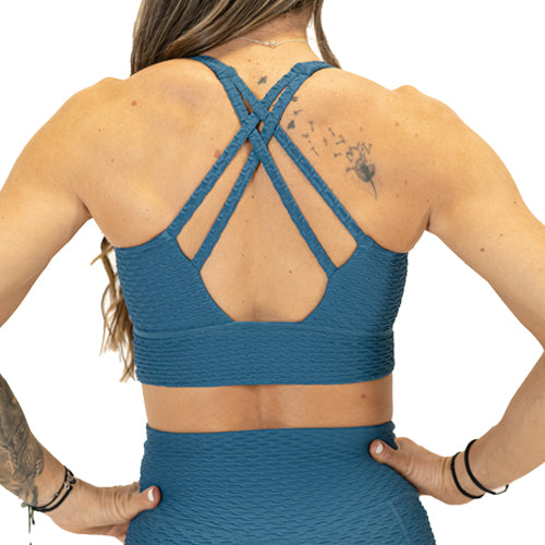 back view of criss cross straps on solid teal textured print sports bra