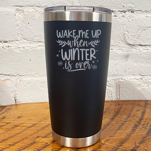 20oz black tumbler with silver saying "wake me up when winter is over" with mini snowflakes around it