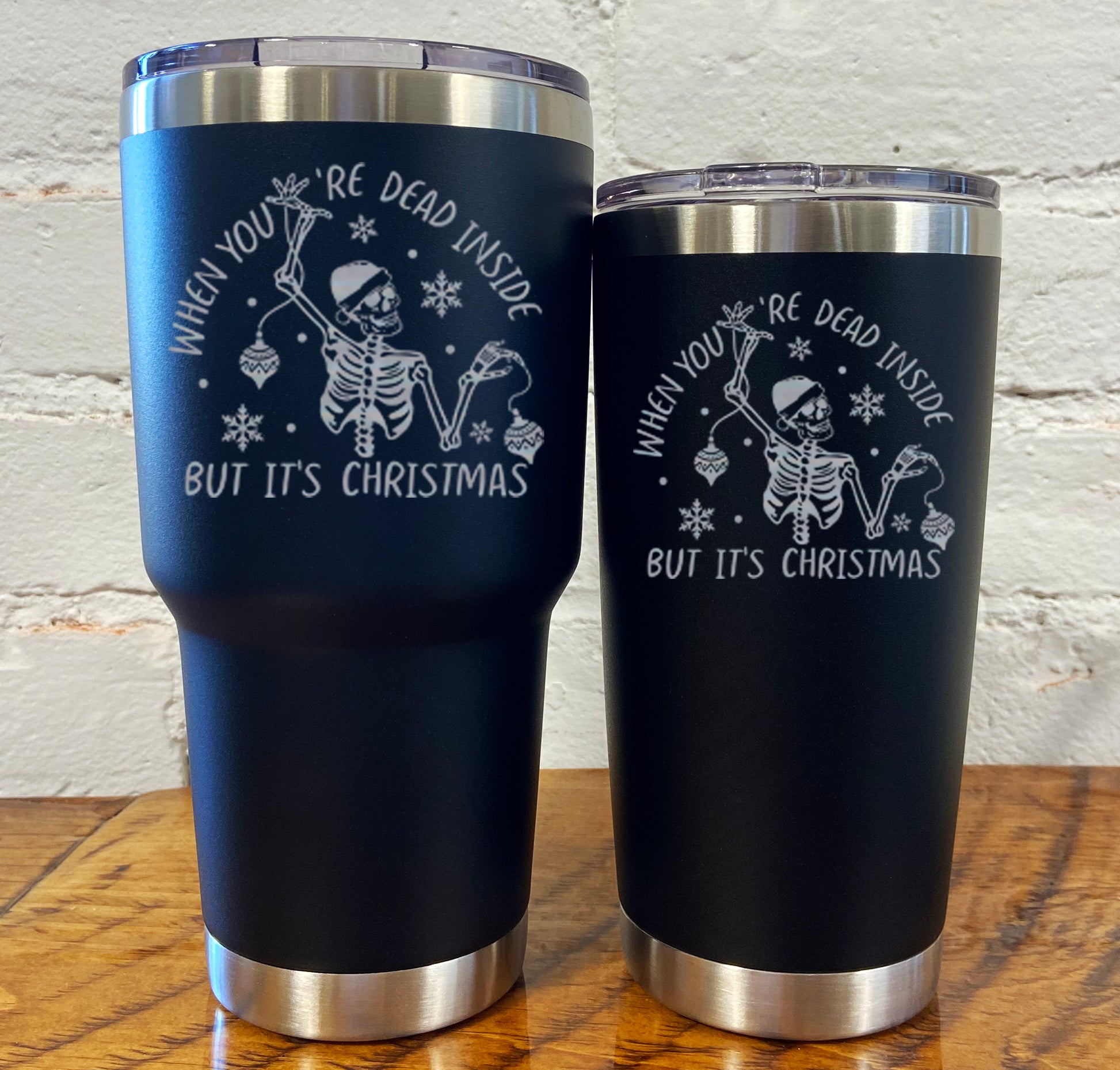 30oz and 20oz black tumblers with silver saying "when you're dead inside but it's christmas" with a santa hat skeleton holding ornaments 