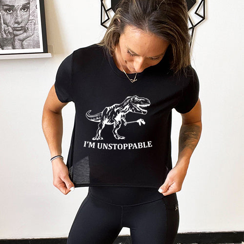 model wearing a black cropped tee with a dinosaur graphic and the words "I'm unstoppable" on the front