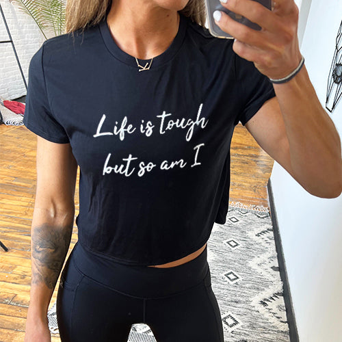 model wearing a black cropped tee with the text "Life is tough but so am I" on the front