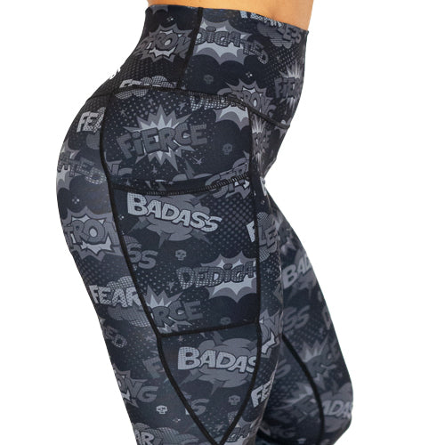 close up of black leggings with comic book style action bubbles that say "badass", "fierce" and "dedication"