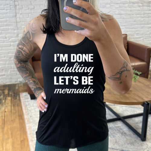 Model wearing a black racerback tank with the saying "I'm done adulting lets be mermaids" in white
