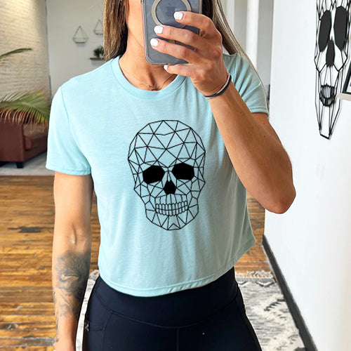 model wearing a dusty blue cropped tee with a geometric skull design on the front in black.