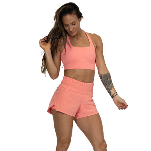 model wearing matching pink peach sports bra and shorts