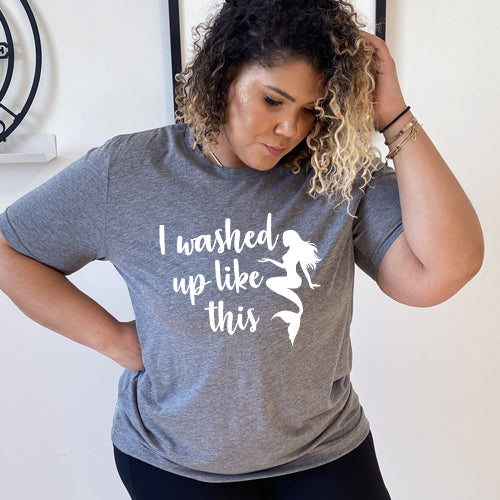 Model wearing a grey unisex tee with the saying "i washed up like this" in white in the center