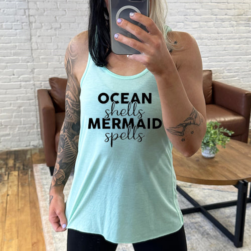 Model wearing a mint racerback tank with the saying "ocean shells mermaid spells" in black in the center