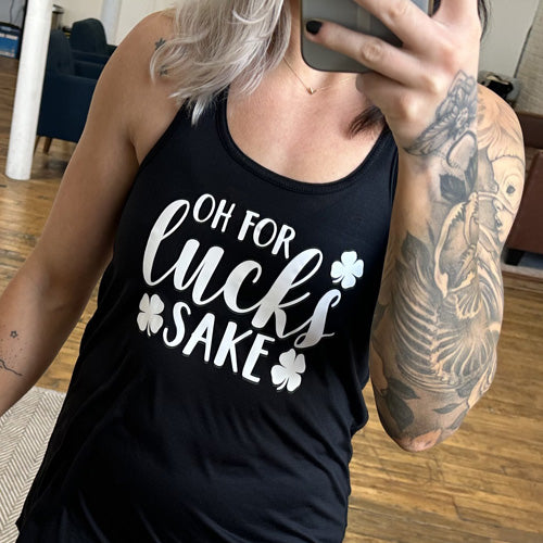 black shirt with the saying "oh for lucks sake" on it in white