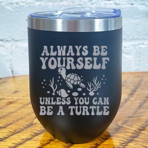 12oz black tumbler with silver saying "always be yourself unless you can be a turtle" with turtle cartoon, seaweed, shells and bubbles