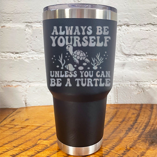30oz black tumbler with silver saying "always be yourself unless you can be a turtle" with turtle cartoon, seaweed, shells and bubbles